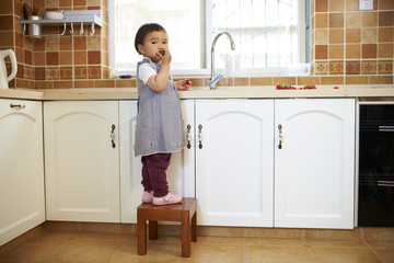 lovely little asian girl eating strawberry in the kitchen