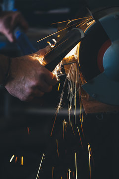Close up of man sharpening an axe with a grinder - horizontal