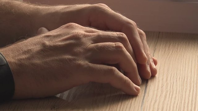 Nervous male hands at office desk, anxiety and anticipation, tension at workplace