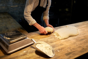 baker portioning dough with bench cutter at bakery