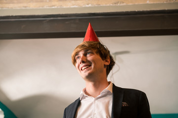 Young adult man celebrating new year eve or eighteenth birthday in cozy apartment indoor