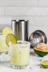 Alcoholic cocktail recipes and ideas. Avocado and lime margarita with salt, on a white marble kitchen table. Copy space