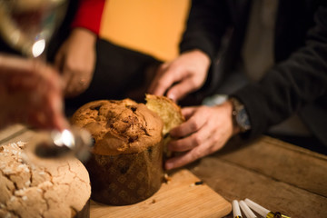 Young adult man celebrating christmas or new year eve slicing traditional italian panettone in cozy...