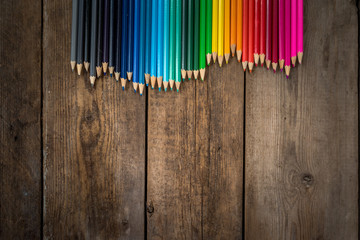 Colored pencils in gradient order located folded on wooden table. School concept. Copy space