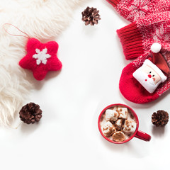 Christmas holiday composition. Hot chocolate with marshmallow, cone, white fur, red felt star, knitted socks on white background. Winter, christmas concept. Flat lay, top view.
