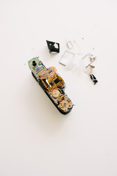 A broken film camera sitting on a white table with parts scattered.