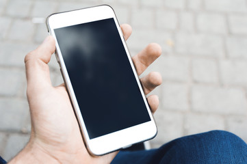 The human hand is using the smart phone. Winter time. Concept waiting or meeting. Outdoor