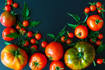 Fresh juicy tomatoes, cherry and leaves pattern and ornament on a dark background with copy space flat view from above