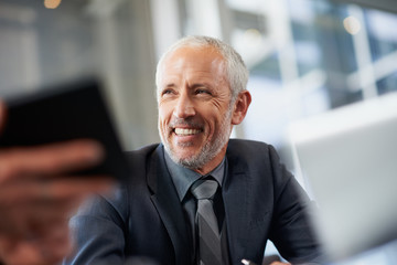 handsome mature businessman smiles in a meeting