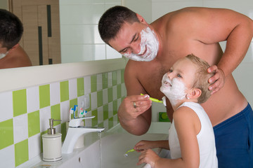 Dad teaches to shave her little son.Child wants to be like dad.	
