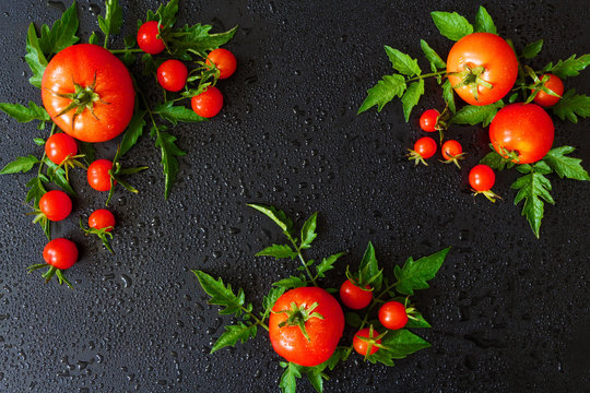 Fresh juicy tomatoes, cherry and leaves pattern and ornament on a dark background with copy space flat view from above