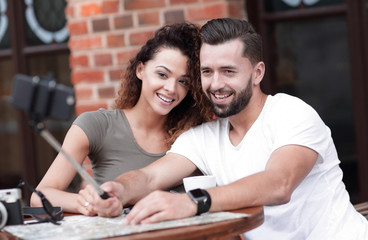 Happy cheerful couple sitting down at a cafe and making selfie