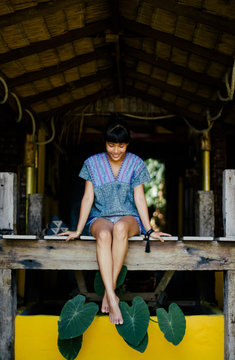 Asian woman sitting on the wooden balcony in tropical house