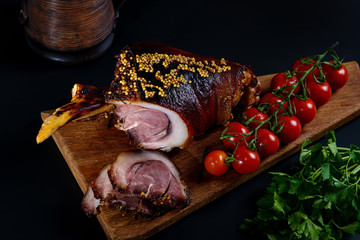 Roast pork knuckle and ingredients close-up on a slate board.