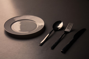 Empty plate with spoon, knife and fork. low key minimalistic picture