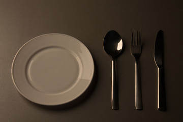 Empty plate with spoon, knife and fork. low key minimalistic picture