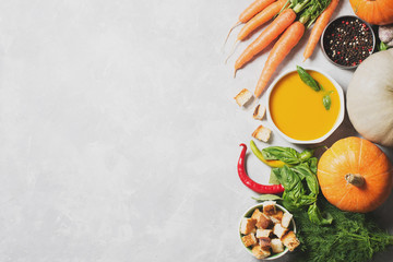 Creamy pumpkins soup with vegetables over grey texture
