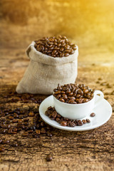 Coffee. A coffee cup with grains and a coffee bag on a wooden table.