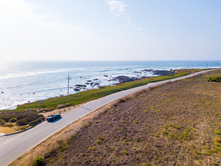 Aerial view of driving in a Ford Mustang convertible down the ocean road in California near the...