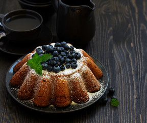 Vanilla cake (gugelhupf) with blueberries. dark background.
