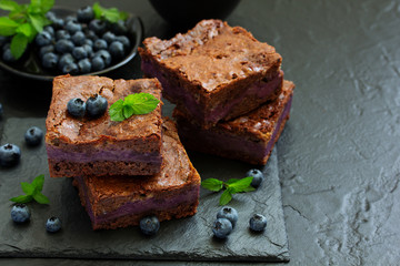 Chocolate brownies with blueberries and cream filling. Dark background.