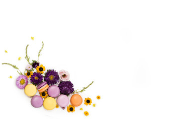 Macarons and flowers wreath on a white background. Colorful french dessert with fresh flowers. Top view