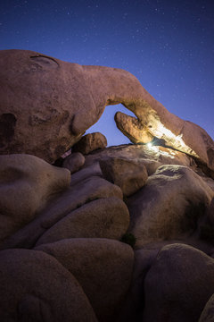 Flashlight Lit Arch Rock Under Night Sky in Joshua Tree National Park, California