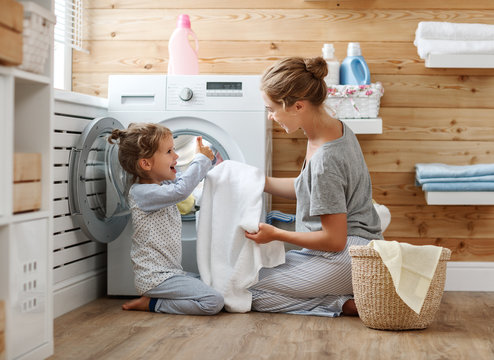 Happy family mother housewife and child   in laundry with washing machine .