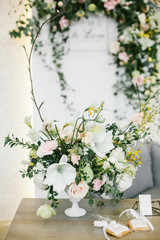 Wedding Table Centerpieces. White floral composition in a white vase on floral background.
