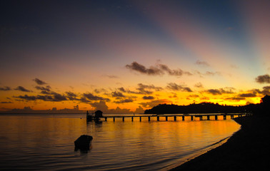 Fototapeta na wymiar Colorful sun ray over the ocean and the dock