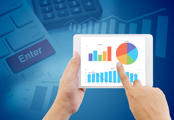 hands of a man holding graph business tablet device on keyboard, graph abstract background