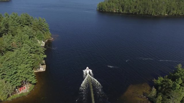 aerial family boat passes through shallow channel cottage country tilt up reveal 4k