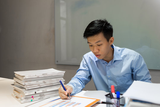 Office employee reading sales report and writing notes