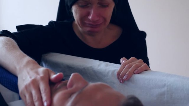 funeral, sadness and mourning concept - sad woman talking and crying next to the coffin. 4k,