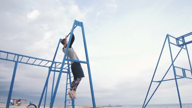 Young man doing parkour tricks on the beach near the sea