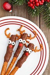Fun Christmas reindeer chocolate dipped pretzel rods, above on a red and white plate