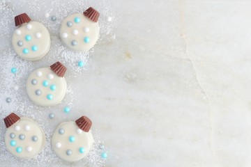 Fototapeta na wymiar Christmas white chocolate ornament cookies, side border on a white marble background