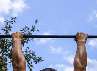 Hands on the bar close-up. The man pulls himself up on the bar. © eleonimages