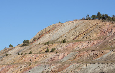 Geological layers of mountain revealed from cutting away part of mountain to make path for Colorado interstate highway 70
