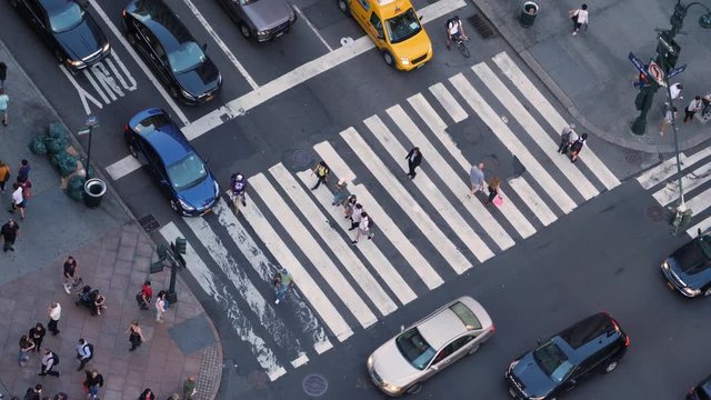 A high angle view of pedestrians and traffic on 5th Avenue in midtown Manhattan.  	