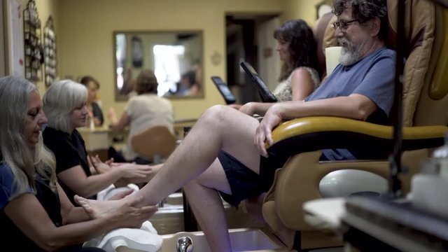 Massage therapists give foot massages to a couple in pedicure chairs.