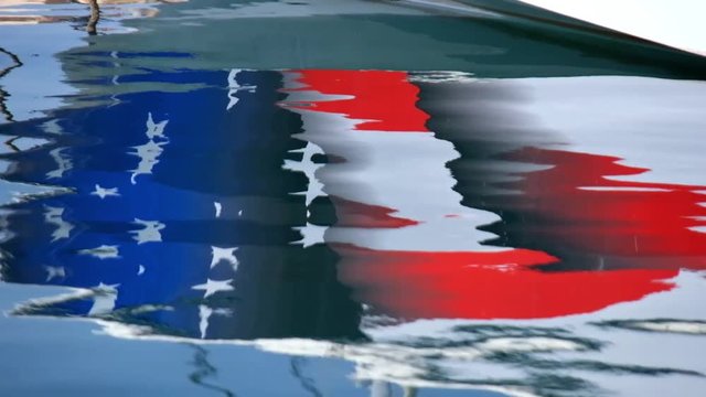 Reflection of Yacht board with american flag  in water