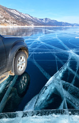 Baikal Lake. The car moves to Sandy Bay (Peschanaya) on a smooth beautiful blue clear ice. Winter extreme ice tourism by car