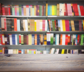 Wooden table over abstract blur background of books on shelves