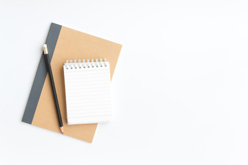 black pencil and notebook paper on brown notebook paper on white background