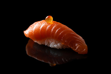 Closeup composition of fresh salmon sashimi sushi with caviar on top on a dark background