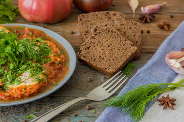 Shakshuka - jewish traditional recipe. Breakfast with fried eggs, tomato sause, pepper and green