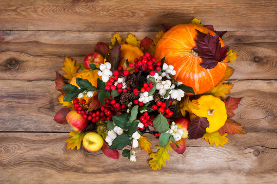 Thanksgiving centerpiece with snowberry and pumpkins on wooden background