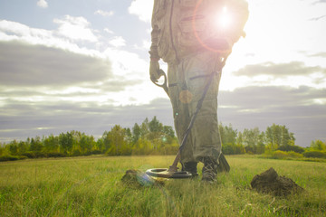 treasure hunter with a metal detector on a beveled wheat field in search of adventure against the...