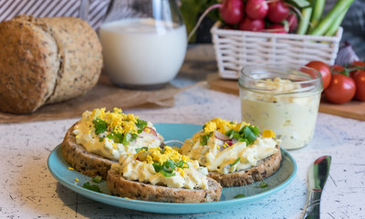 egg spread on round fresh homemade bread, decorated with spring onion and crushed yolk
